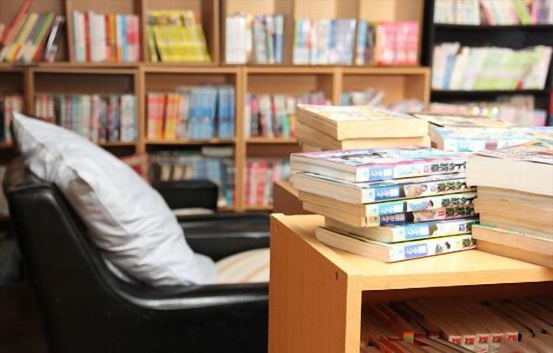 A library with bookshelves filled with books and a stack of books on a table.