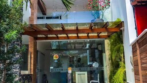 A modern house with a glass entrance, a wooden pergola, and a small garden with plants and a pathway. - Cristal Pousada (Cairu)