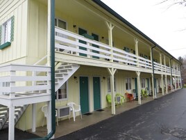 Un motel con una estructura de dos pisos, un porche cubierto y una escalera que lleva al nivel superior.