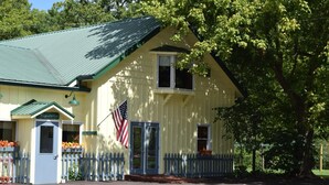 A yellow building with a green roof, a blue door, and an American flag.