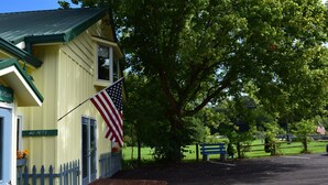 A yellow building with a blue door and a 'NO PETS' sign, an American flag, and a wooden ramp leading to the entrance.