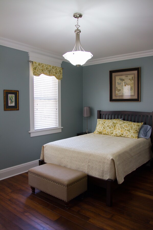 A bedroom with a bed, a window with blinds, a bedside lamp, and a framed picture on the wall. - Wishmaker House B&B (Bellville)