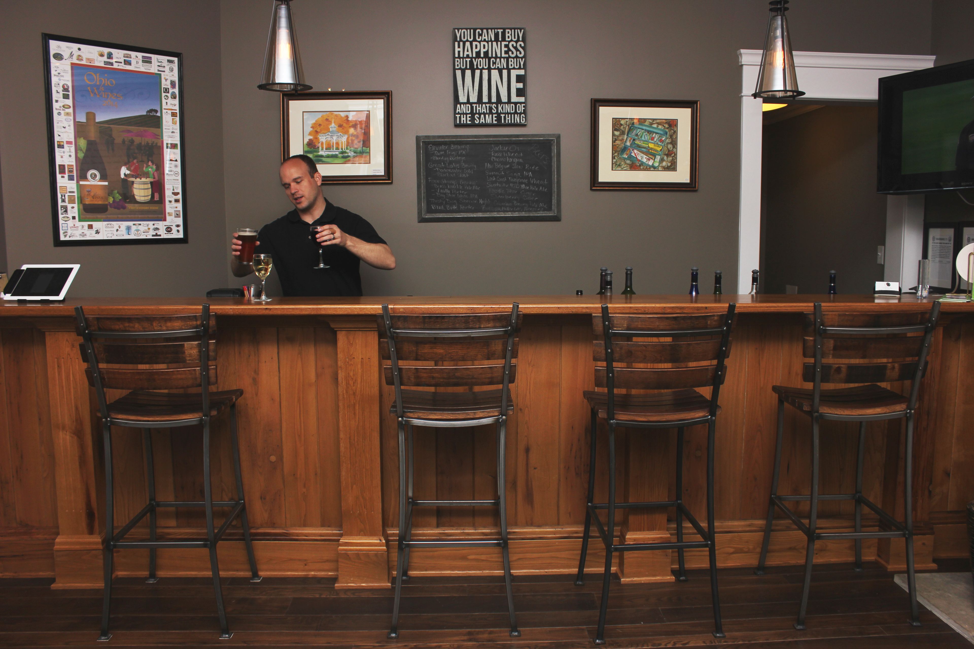 A bar area with wooden bar counter, metal stools, and framed artwork on the wall.