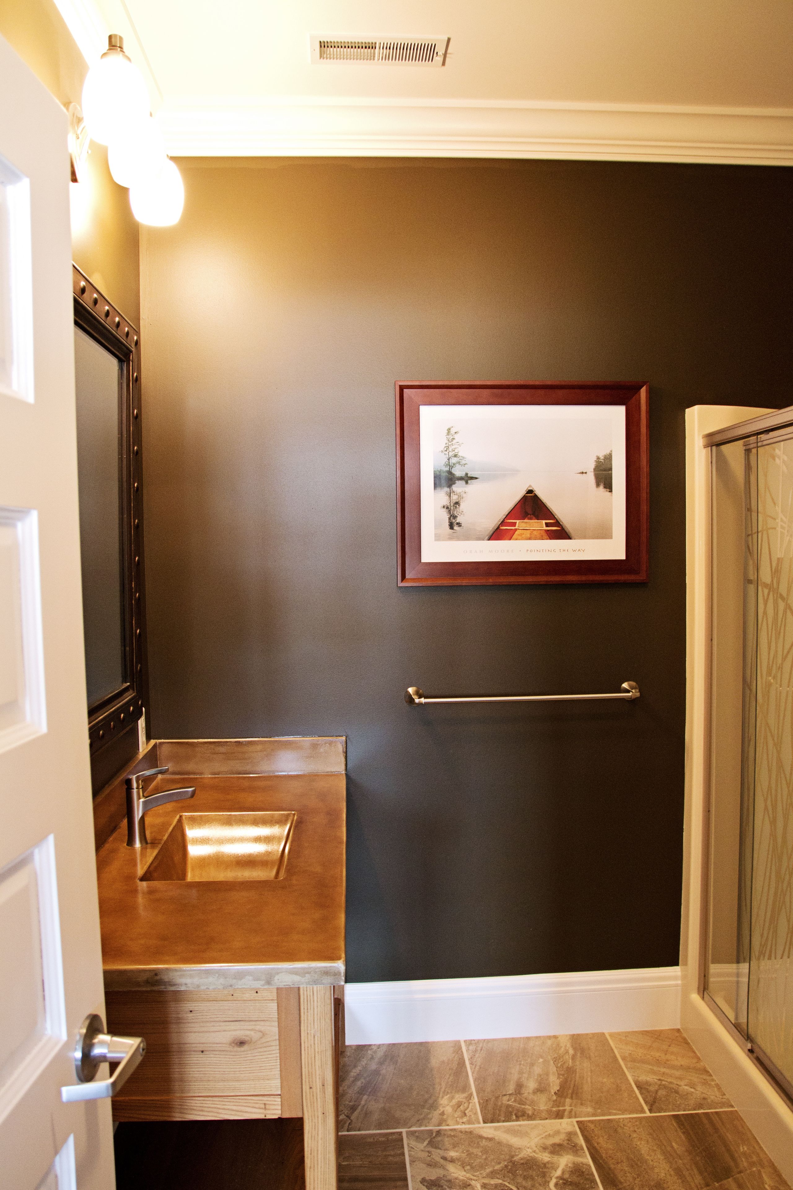 A bathroom with a wooden vanity, a framed picture on the wall, and a towel rack.
