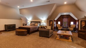 A spacious loft bedroom with a large bed, a sofa, a coffee table, and a fireplace. - Wishmaker House B&B (Bellville)