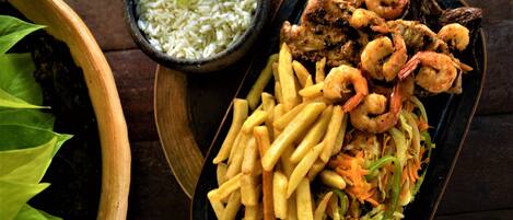 A meal consisting of shrimp, fries, and rice served on a wooden table.