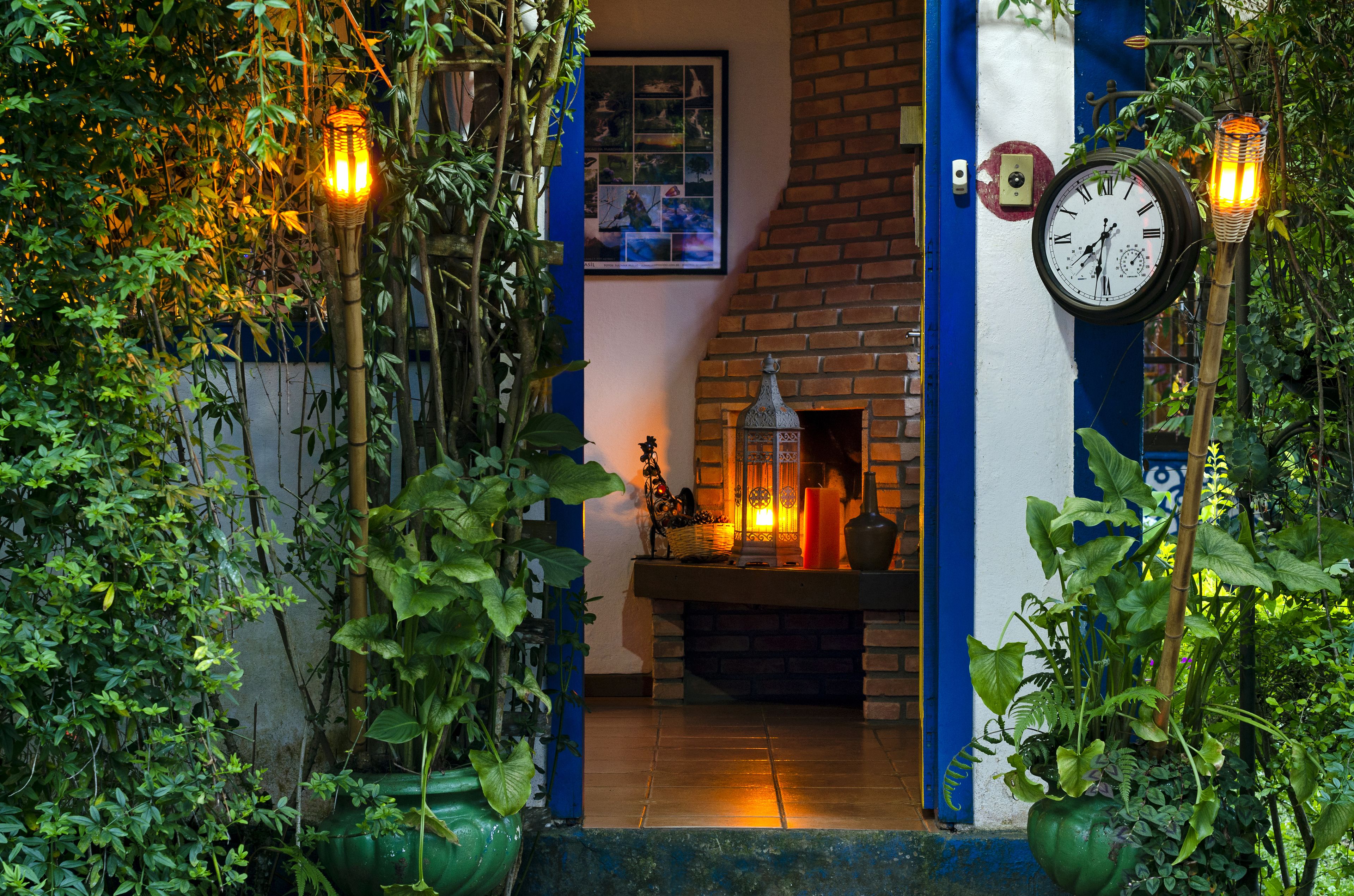 A cozy entrance with a brick fireplace, a clock, and potted plants.