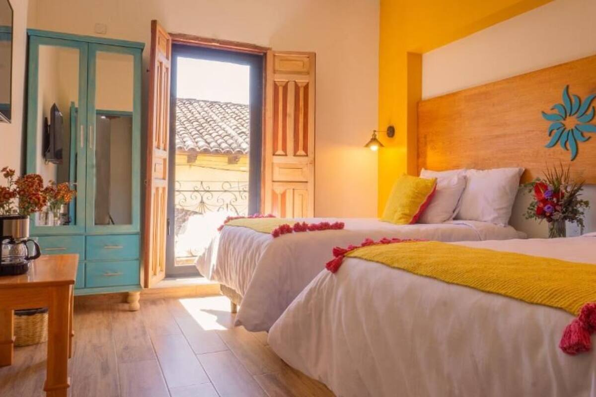 Une chambre d’hôtel avec deux lits, une tête de lit en bois, un élément décoratif mural et une vue sur l’extérieur.