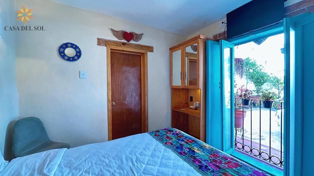 Une chambre à coucher comprenant un lit, une armoire, une chaise et une fenêtre donnant sur l’extérieur.