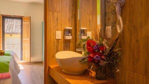 A bathroom with a large, round sink, a mirror, and a vase of flowers on the counter. - Hotel Casa del Sol (San Cristóbal de las Casas)