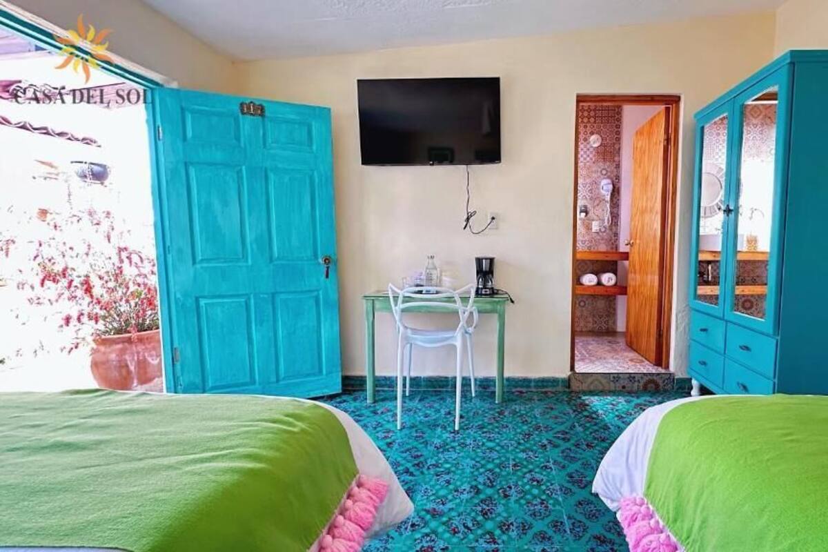 Une chambre avec deux lits, un bureau avec une chaise, une télévision et une armoire.