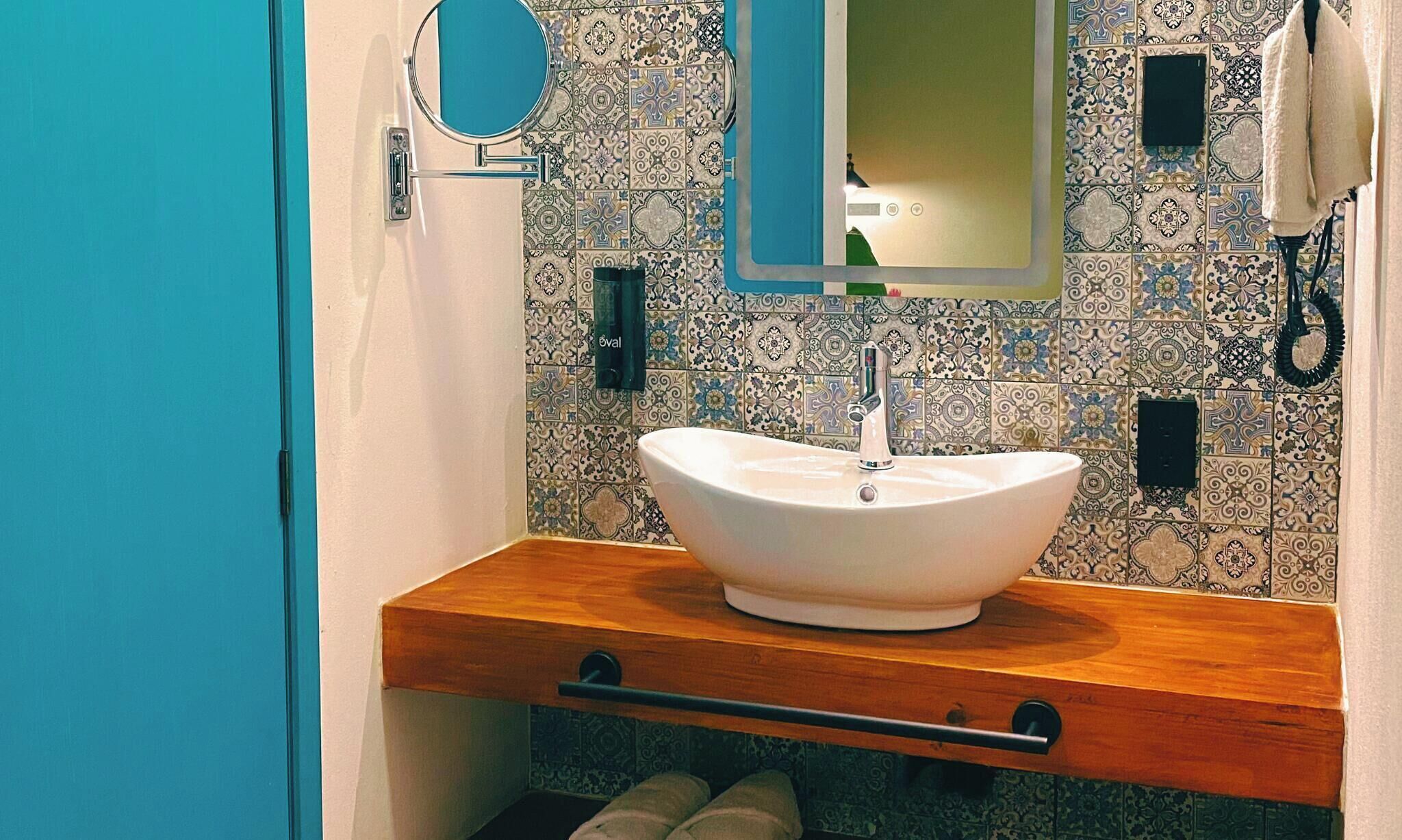 A bathroom with a white sink, a mirror, and a towel rack.