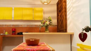 A kitchen with yellow cabinets, a coffee maker, and a vase with flowers on the counter. - Hotel Casa del Sol (San Cristóbal de las Casas)
