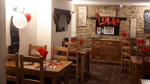 A cozy dining area with wooden tables and chairs, a stone wall with a neon 'Love' sign, and a menu board. - Winchester Arms (Taunton)