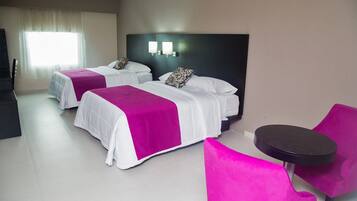Quarto de hotel com duas camas, uma mesinha e uma cadeira.