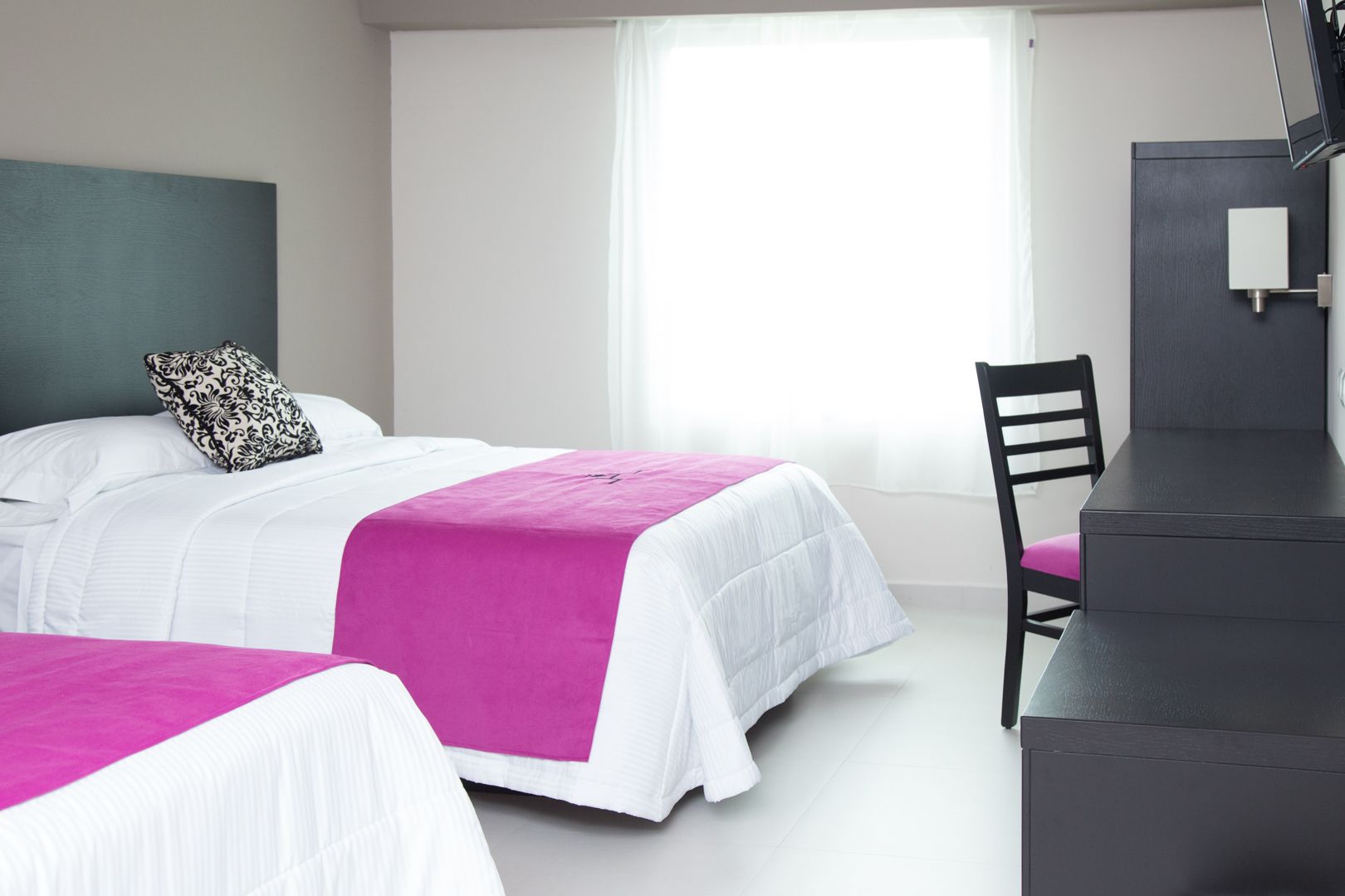 Habitación de hotel con dos camas, un escritorio y una silla.