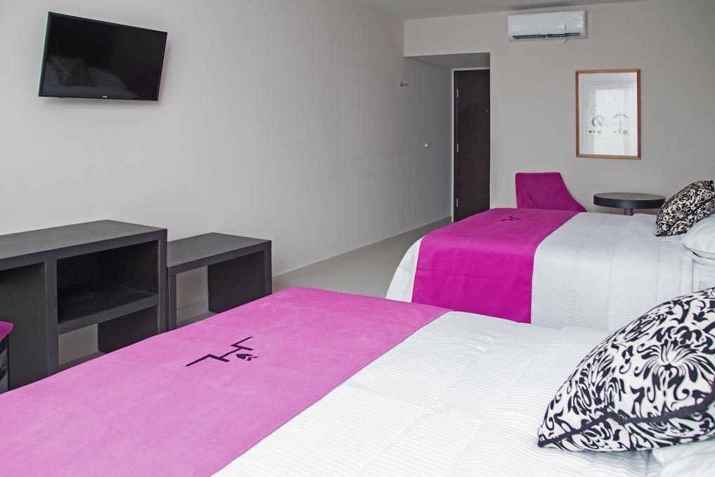 Une chambre d’hôtel avec deux lits, une télévision, un bureau et une chaise.
