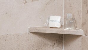 Una repisa de baño con una pastilla de jabón y una botella de champú.