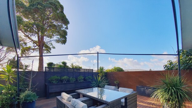 A patio with wicker furniture and potted plants. - Alice House (Auckland)