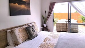 A bedroom with a bed, a painting, a potted plant, and a view of the outdoors. - Alice House (Auckland)