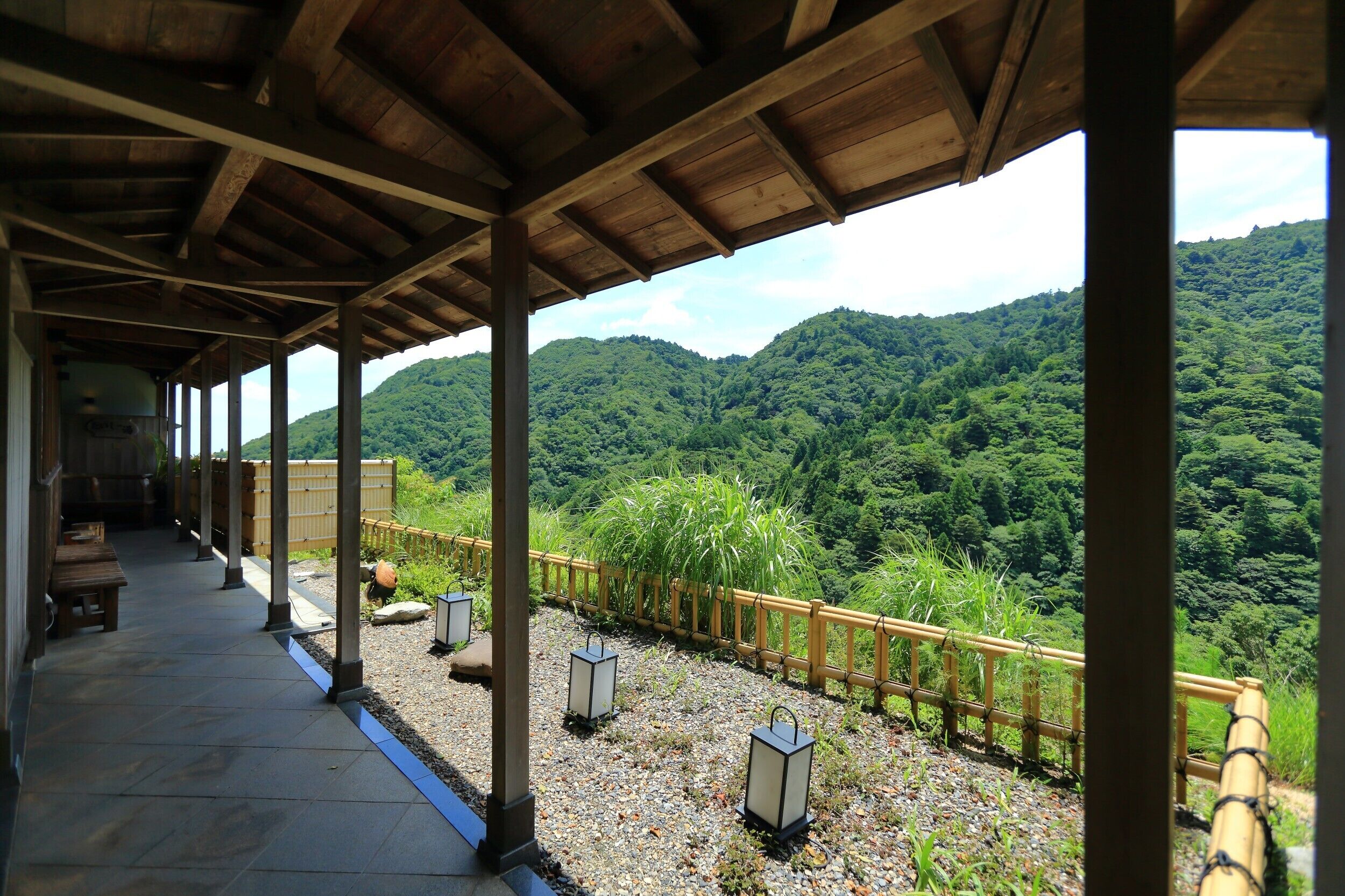 Un espacio al aire libre techado con cubierta de madera, suelo de piedra y faroles.