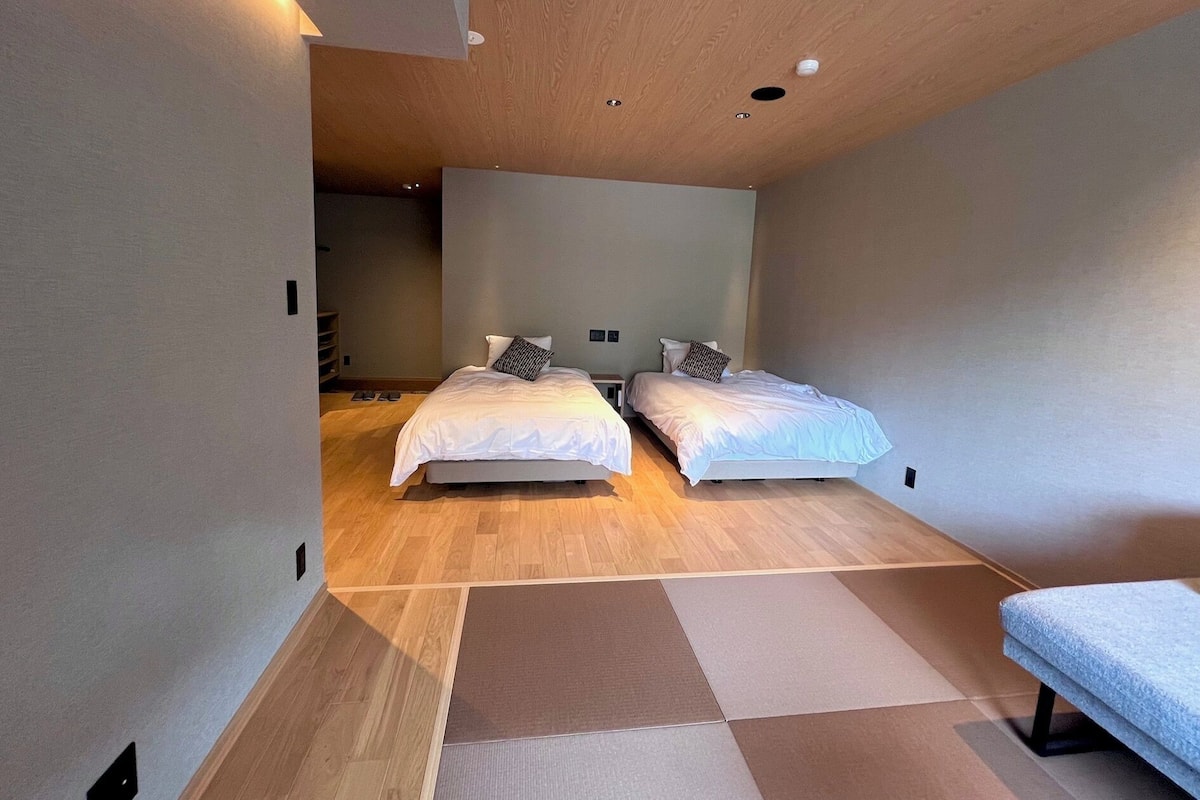 Une chambre moderne avec deux lits, un plancher en bois et un banc.