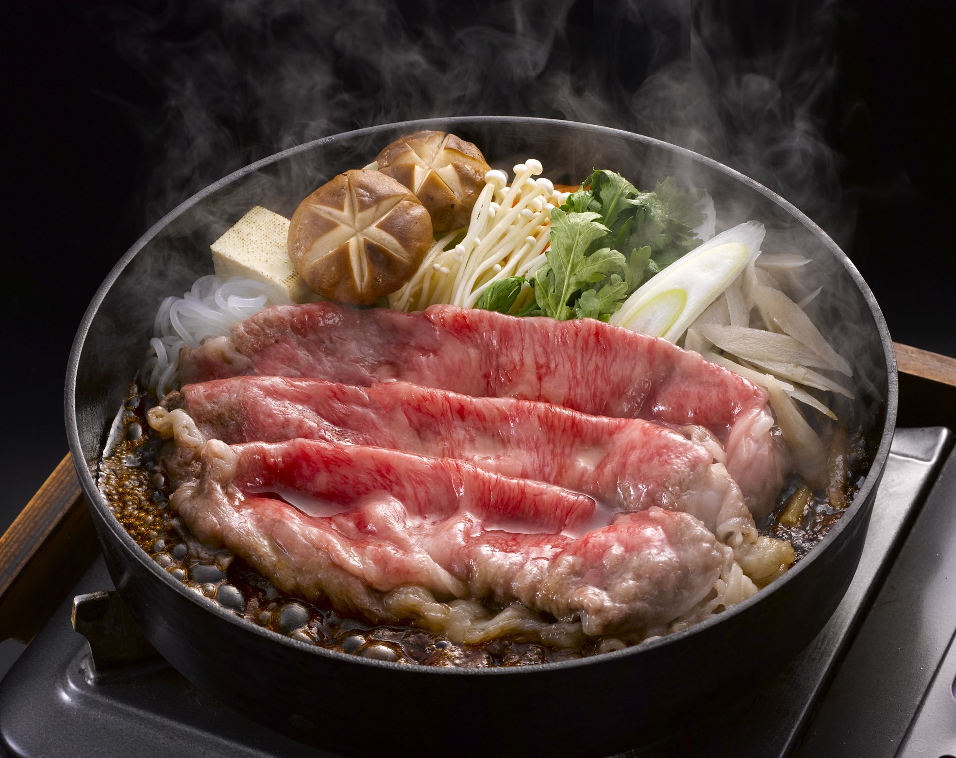 Un tazón de ramen con lonjas de carne, fideos, hongos y verduras.
