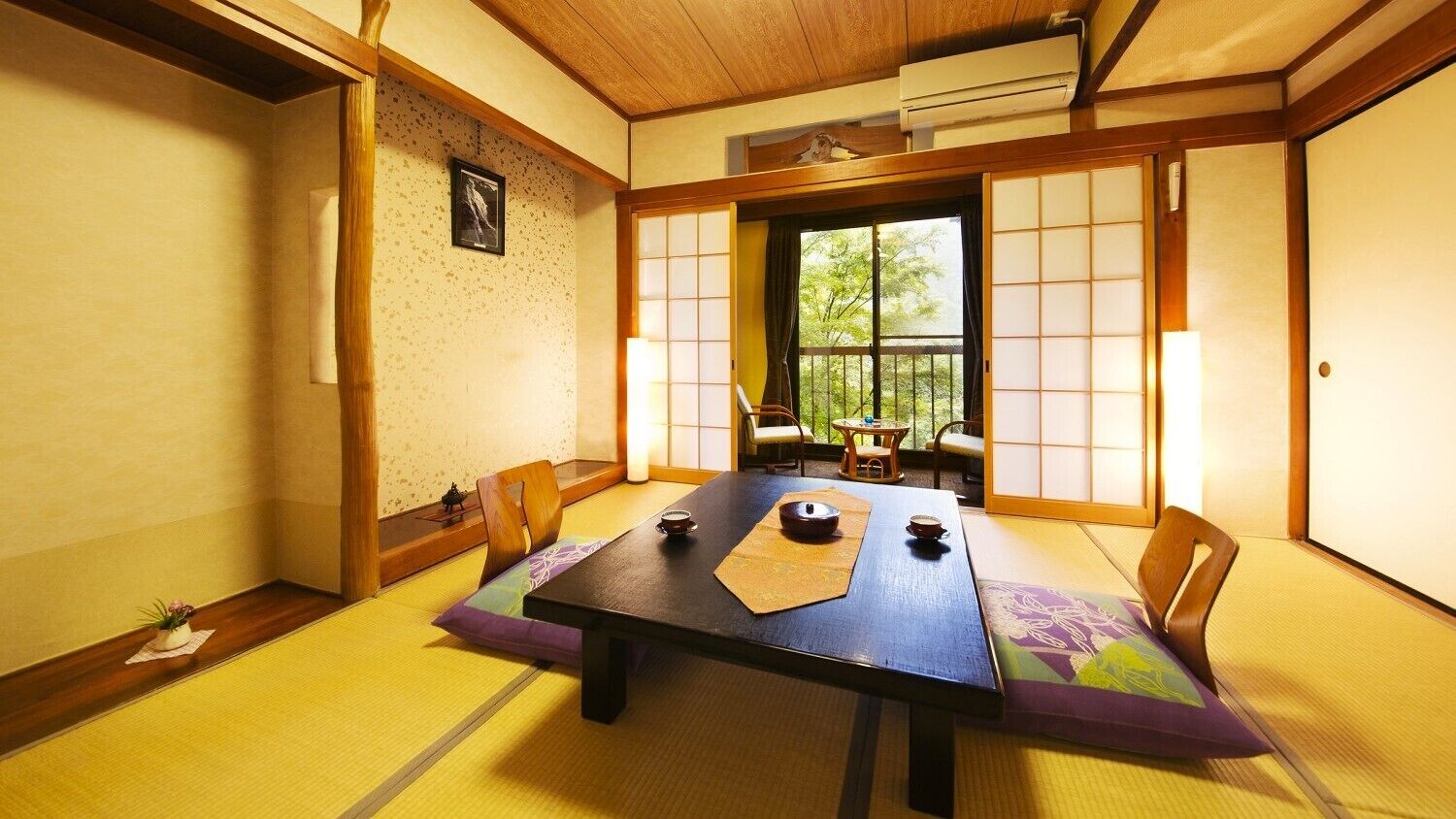 Ein traditioneller japanischer Raum mit Tatami-Böden, einem niedrigen Tisch mit Teeutensilien, Schiebetüren und Blick ins Grüne.