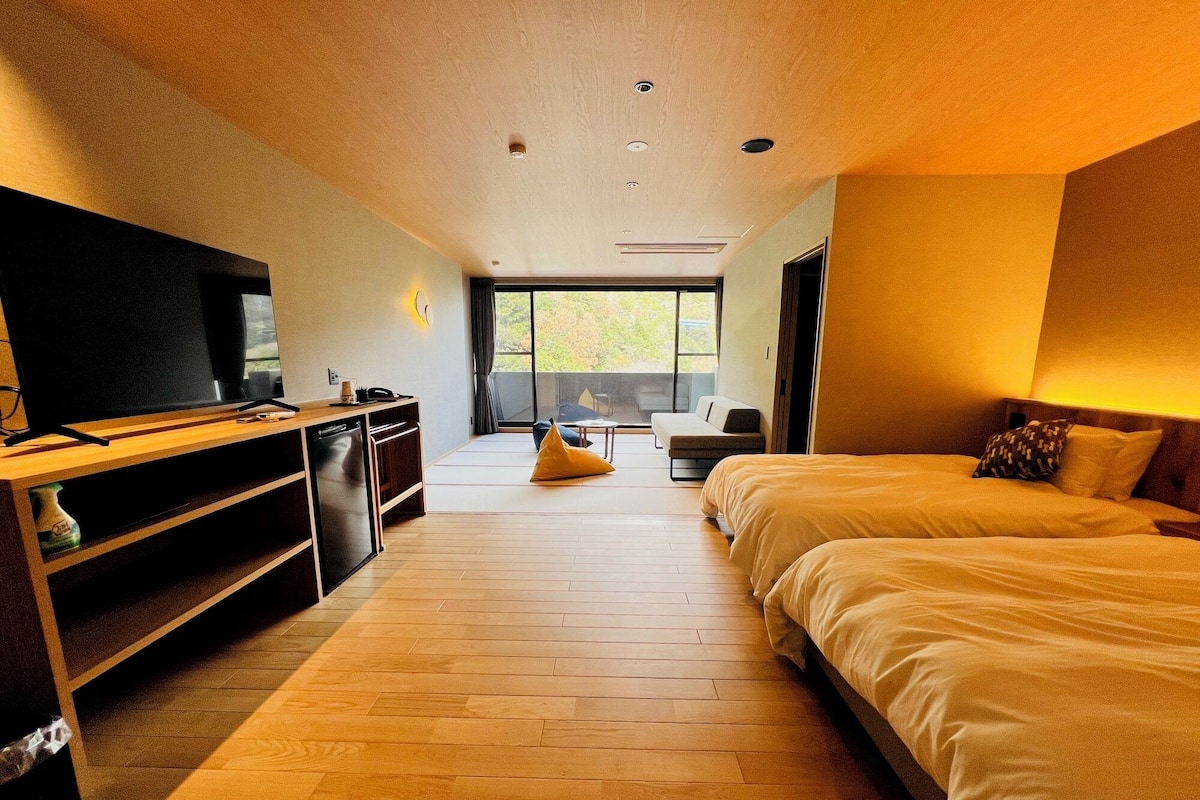Une chambre moderne avec un grand lit, une télévision, un bureau et un balcon offrant une vue agréable.