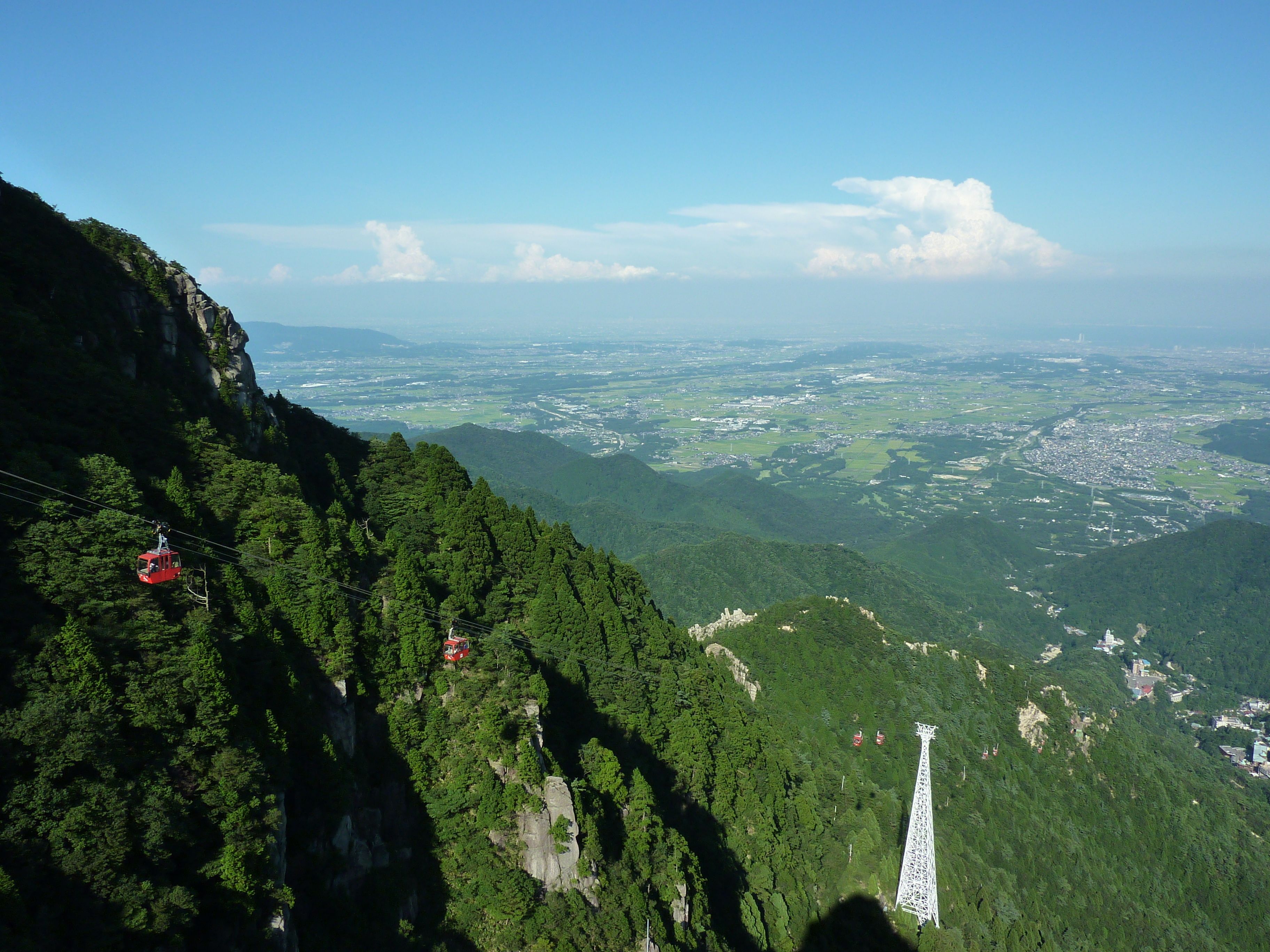 A cable car system in a mountainous area with a view of a town below.