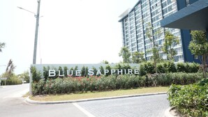 A sign for 'BLUE SAPPHIRE' with a modern building in the background. - Baan Thew Talay Blue Sapphire (Cha-am)