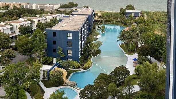 A resort with a large pool area, a building with multiple floors, and a view of the ocean. - Baan Thew Talay Blue Sapphire (Cha-am)