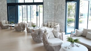 A spacious lounge area with wicker furniture and large windows offering views of the outside. - Baan Thew Talay Blue Sapphire (Cha-am)