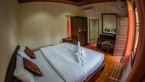 Une chambre d’hôtel avec un grand lit, un bureau, une armoire et une salle de bain visible à travers une porte ouverte.