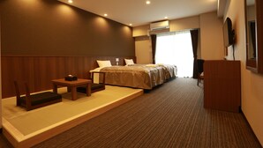 Quarto de hotel com cama, escrivaninha, cadeira, mesinha e ar condicionado.