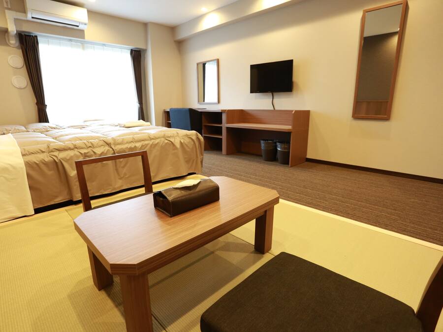 Een hotelkamer met een bed, een bureau, een stoel, een televisie en een spiegel.