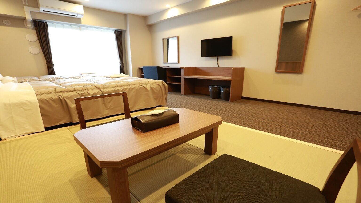 A hotel room with a bed, a desk, a chair, a television, and a mirror.
