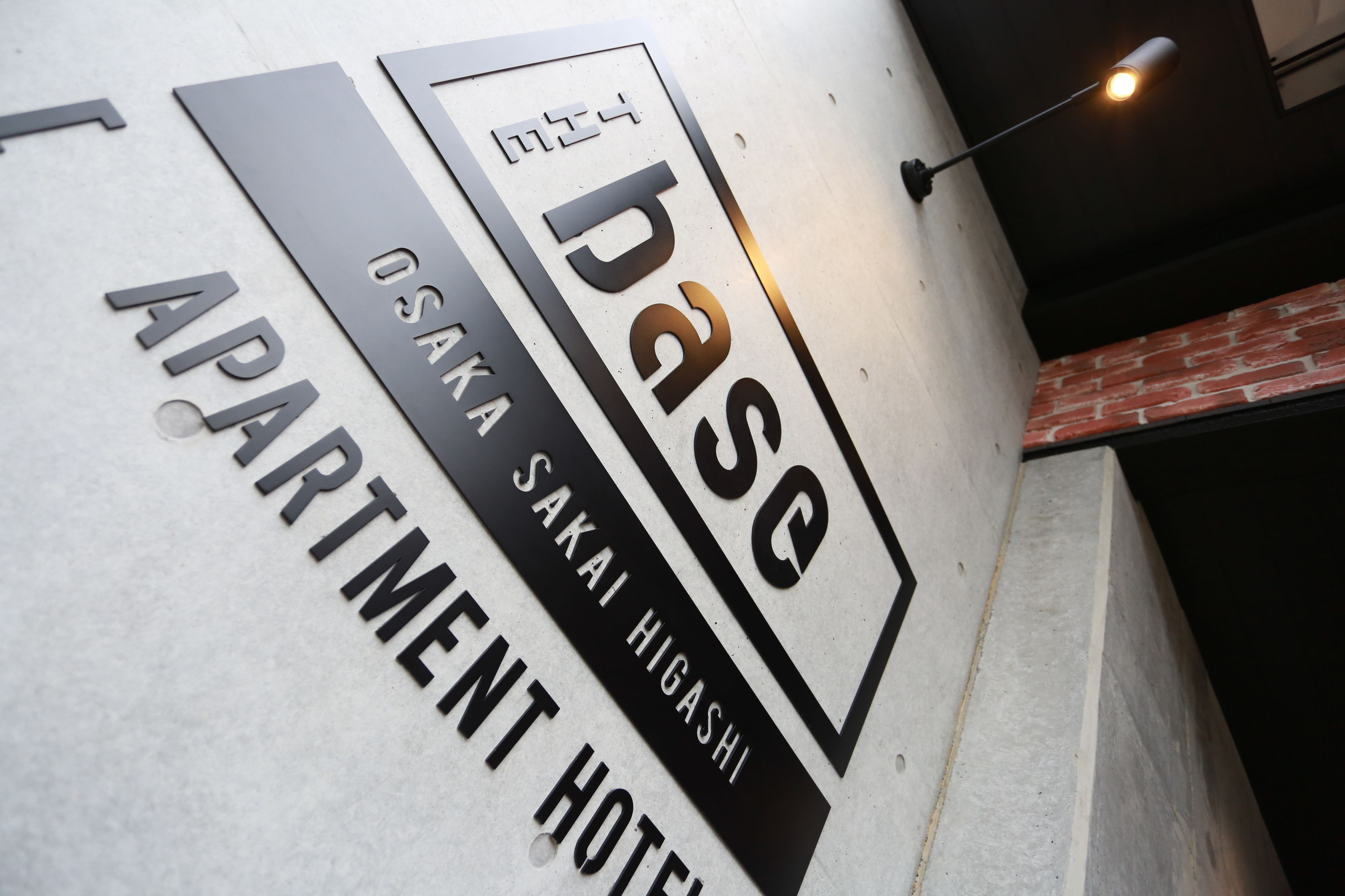 A wall with the text "base" and "OSAKA SAKAI HIGASHI APARTMENT HOTEL".