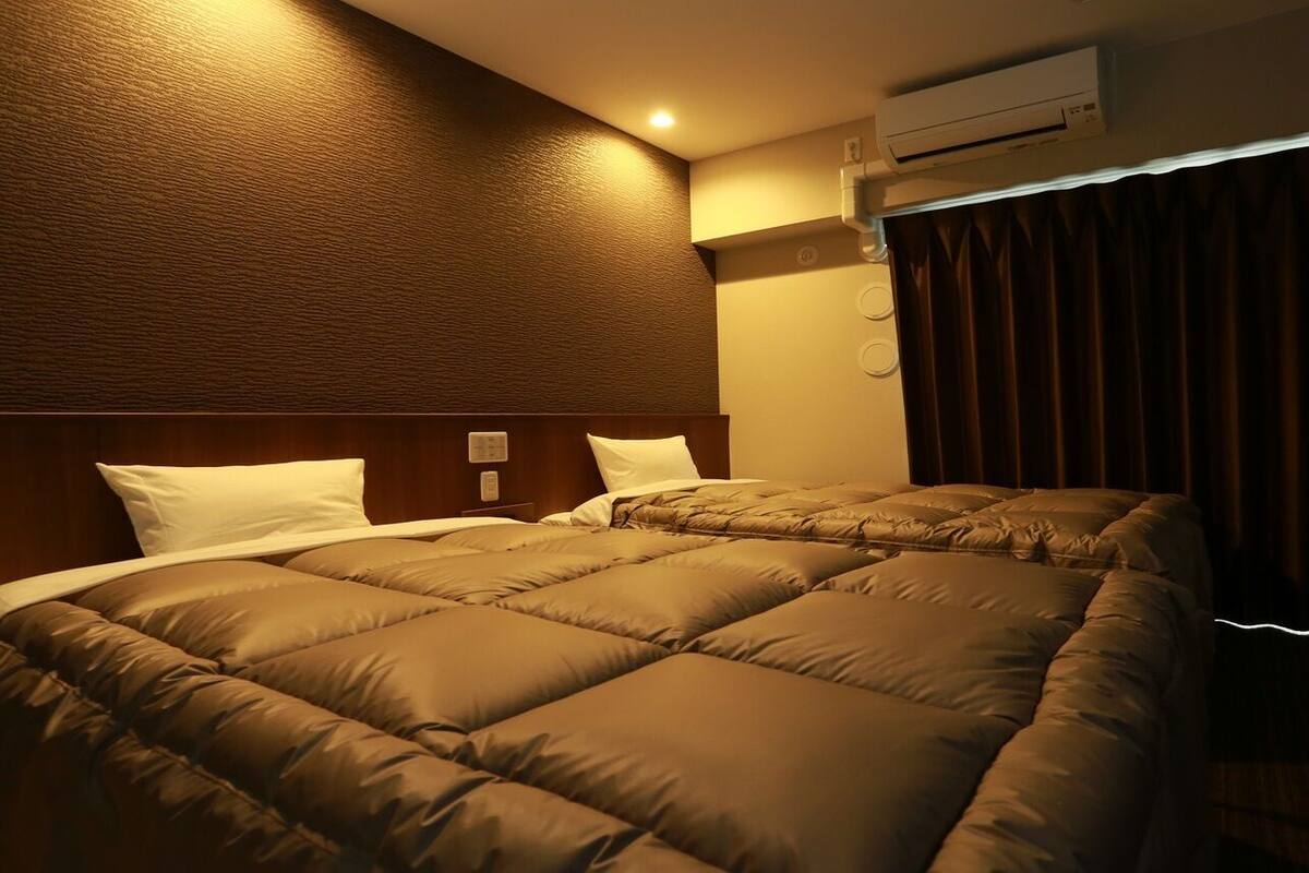 Een hotelkamer met een groot bed, een airconditioning en een raam met gordijnen.