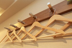 Una stendibiancheria in legno con mollette metalliche su una parete beige.