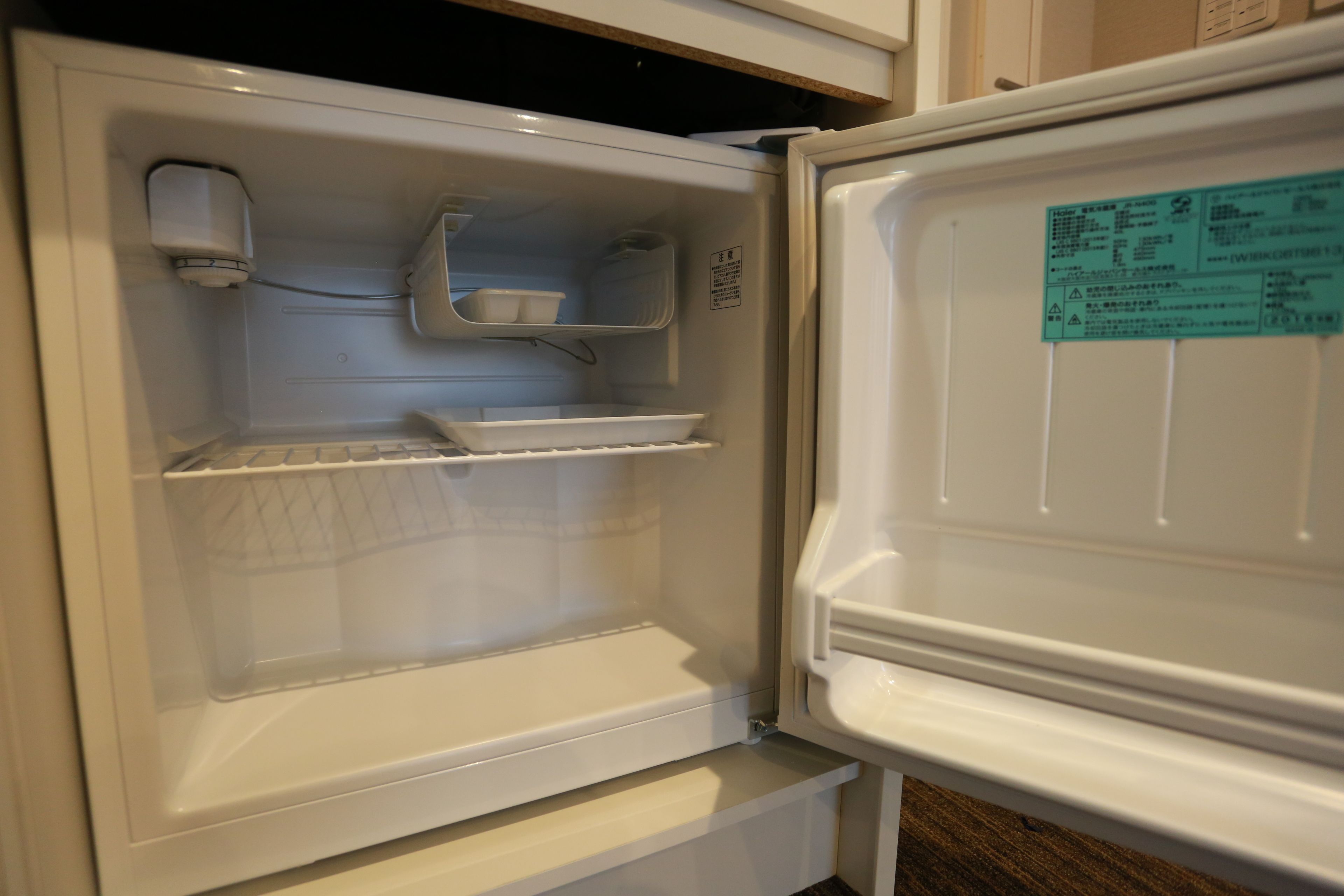 An open refrigerator with shelves and a water dispenser.