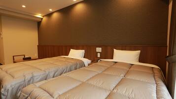 Habitación de hotel con dos camas, cabecera de madera y una mesita de noche.