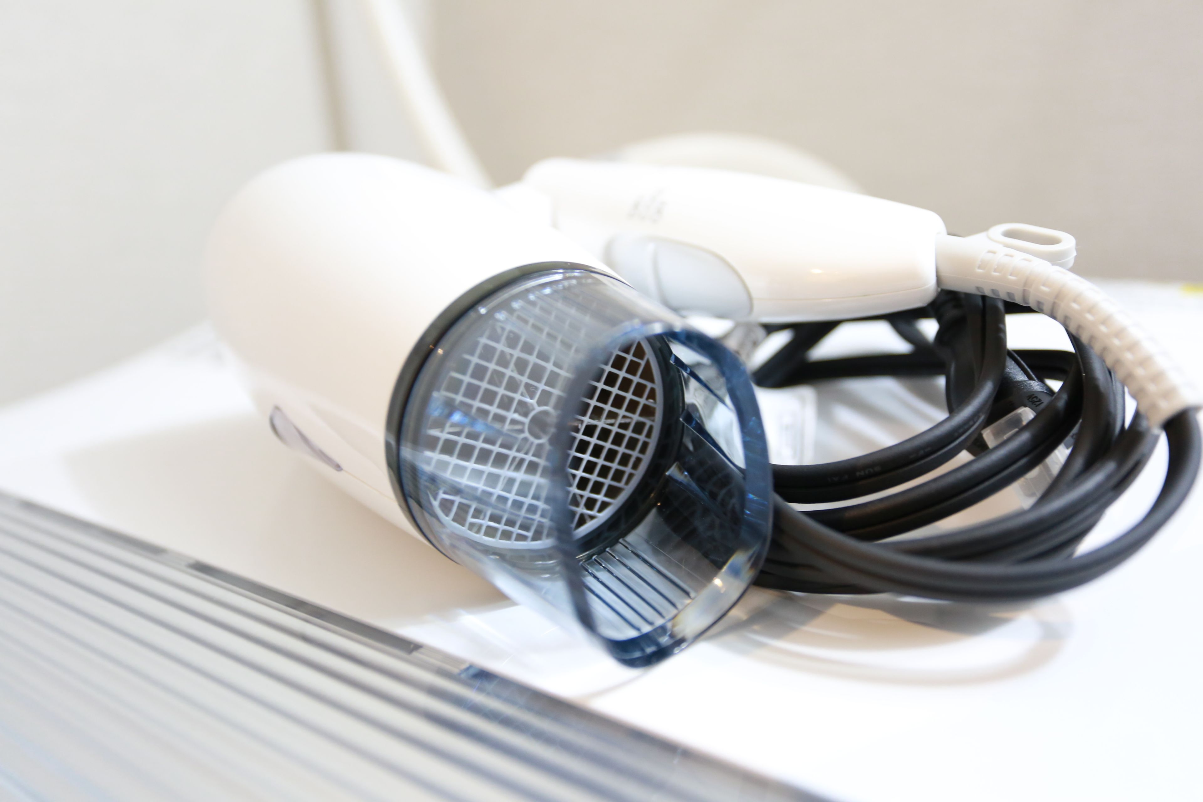 A hairdryer with a cord and a protective cover on a white surface.