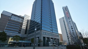 Um edifício moderno com fachada de vidro e uma placa com caracteres japoneses.