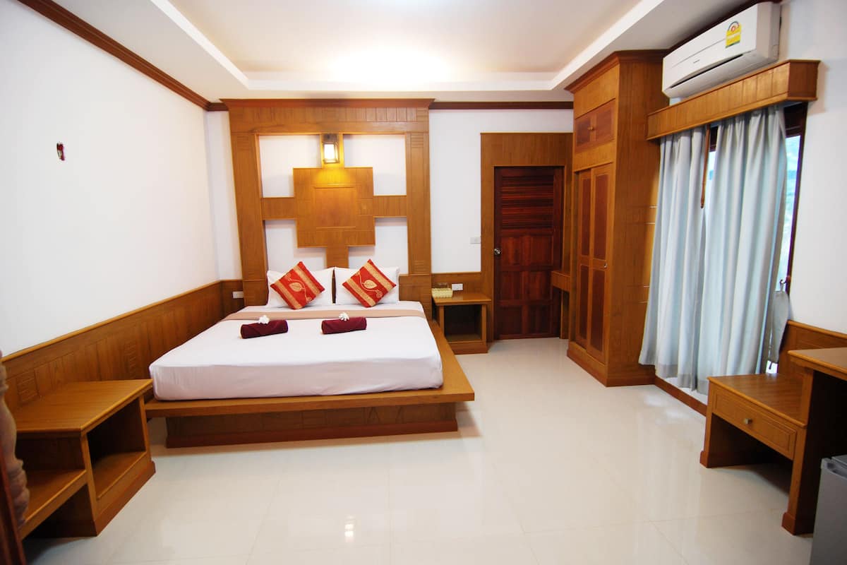A hotel room with a wooden bed, a nightstand, a desk, and a wardrobe.