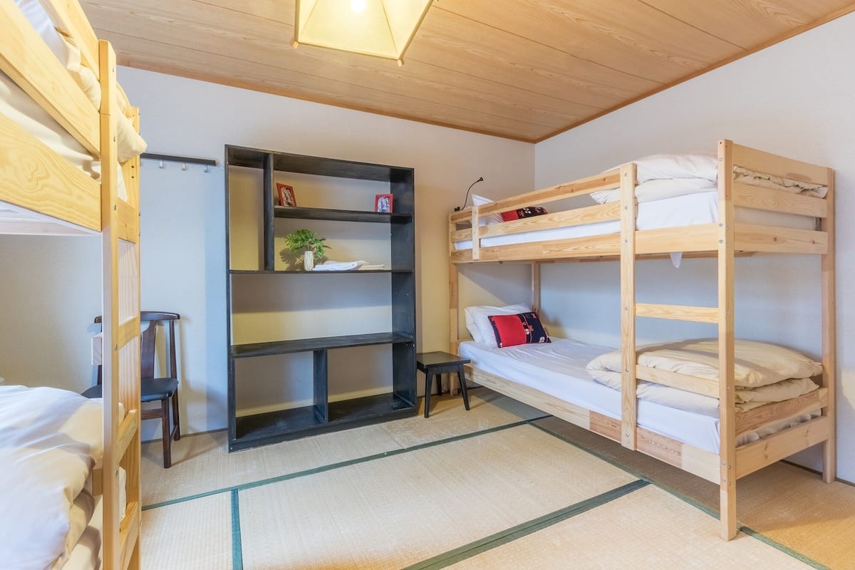 A bunk bed room with a shelf unit and a small table.