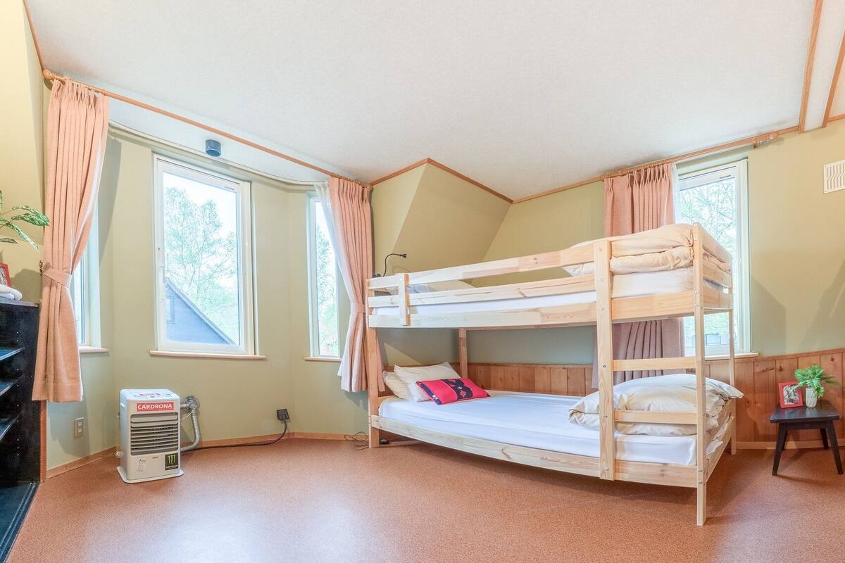 A bunk bed room with a radiator, a small table, and a window with curtains.