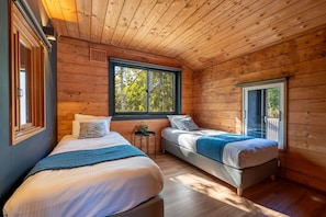 Une cabine avec deux lits, une fenêtre et une porte donnant sur l’extérieur.
