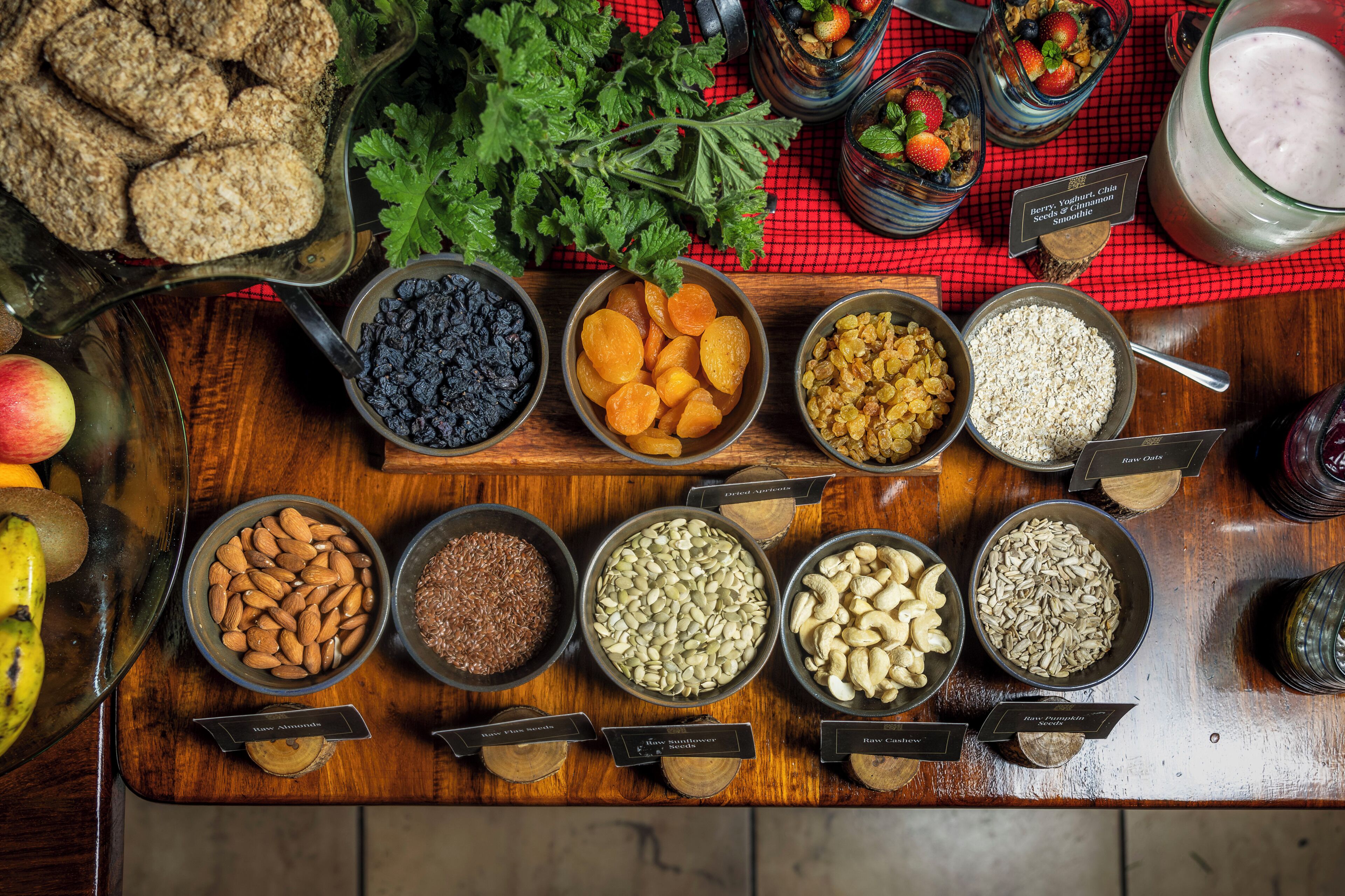 Une variété de fruits secs et de noix disposés sur une table en bois, avec des étiquettes indiquant leurs différents types.