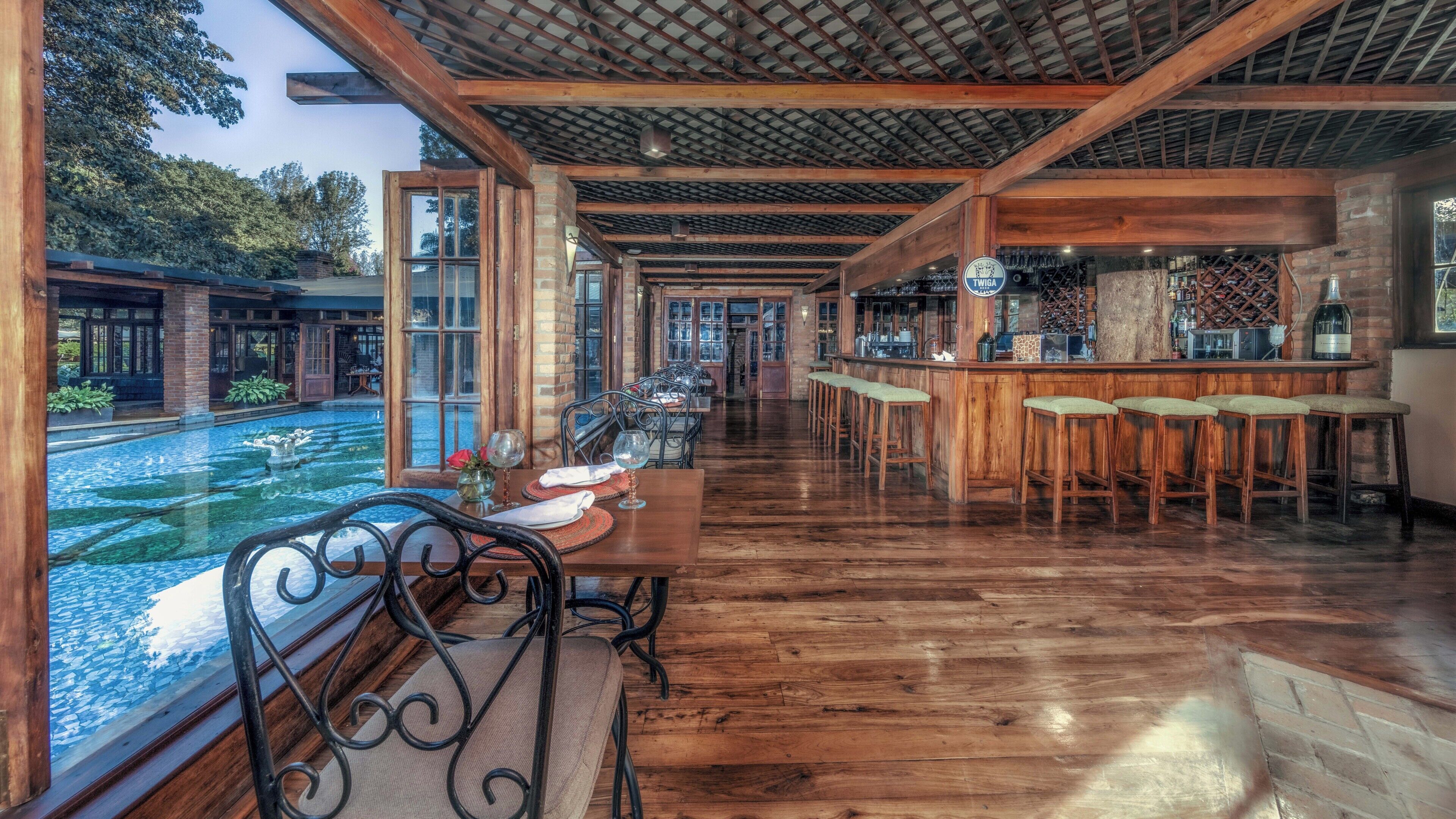 A restaurant with a long wooden table and chairs, a bar area, and a view of a pond.